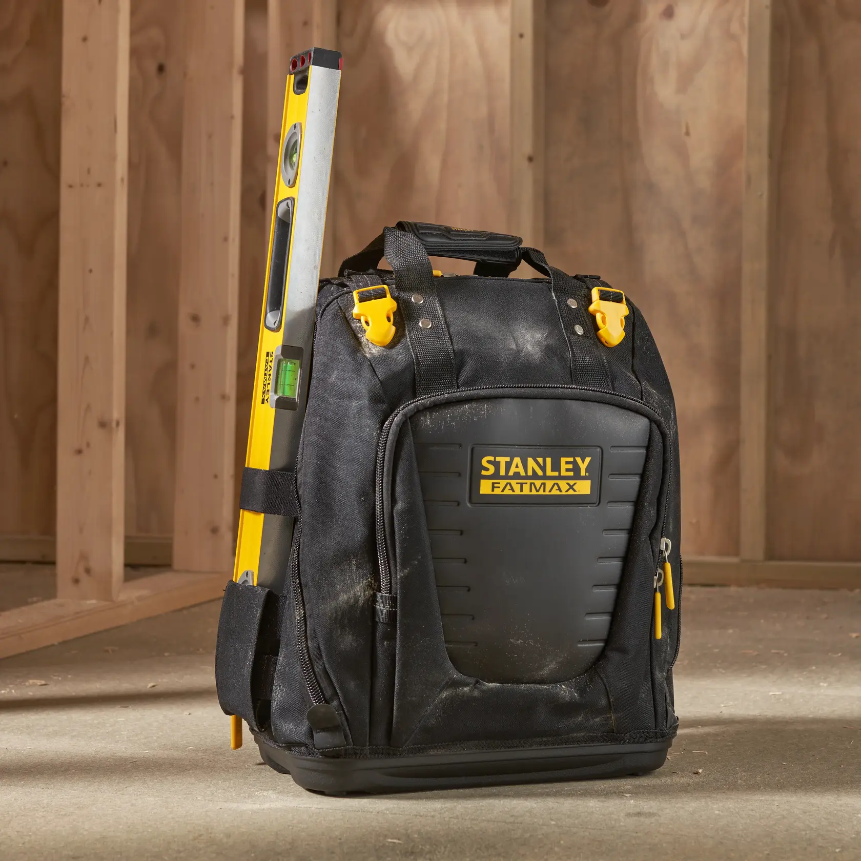STANLEY FMST1-80144 mochila para herramientas con nivel, negra con amarillo, sobre el suelo.