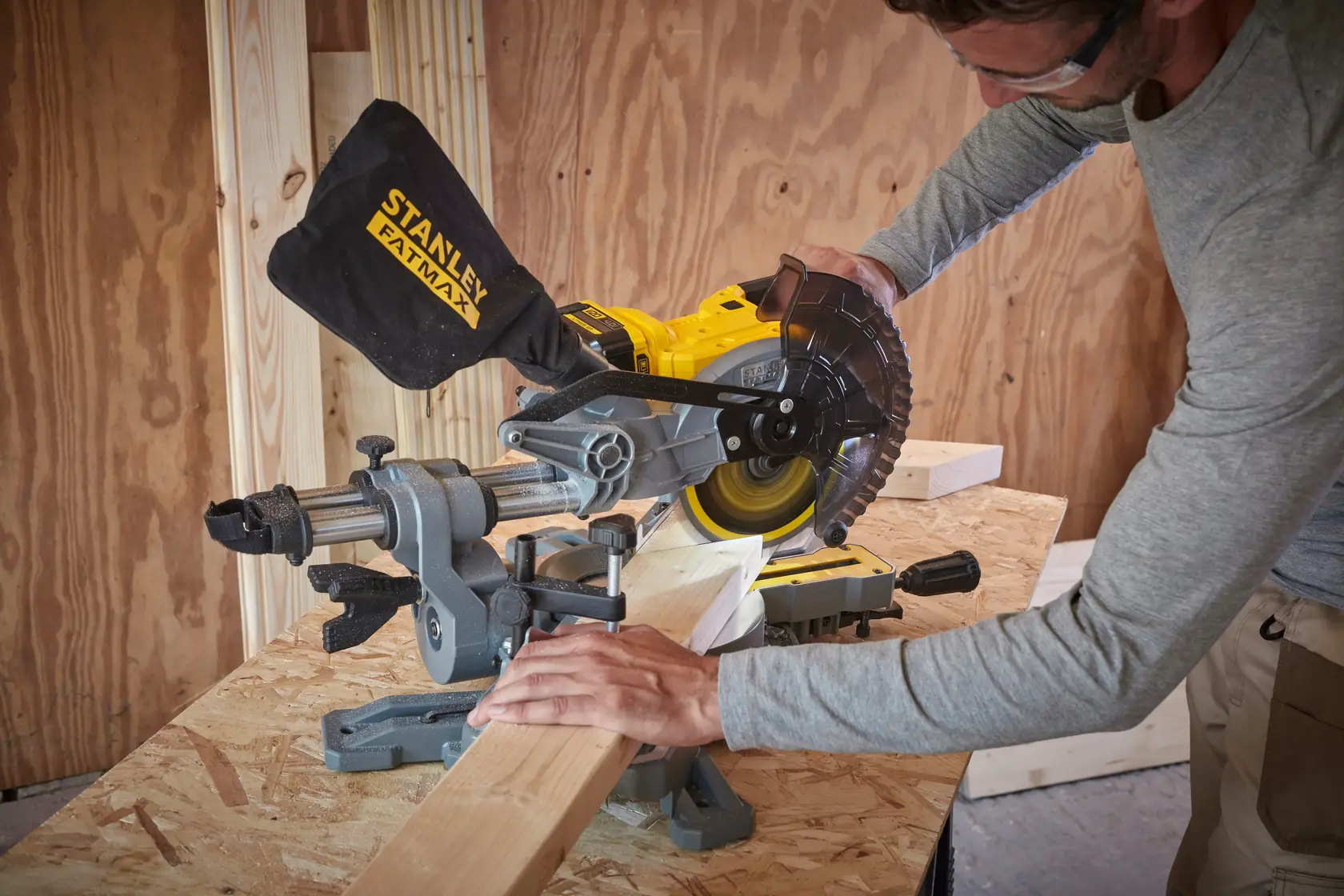 Fotografía de STANLEY FATMAX miter saw, SKUs SCM701-B3, SCM701-B2, SCM701, cortando madera en taller.