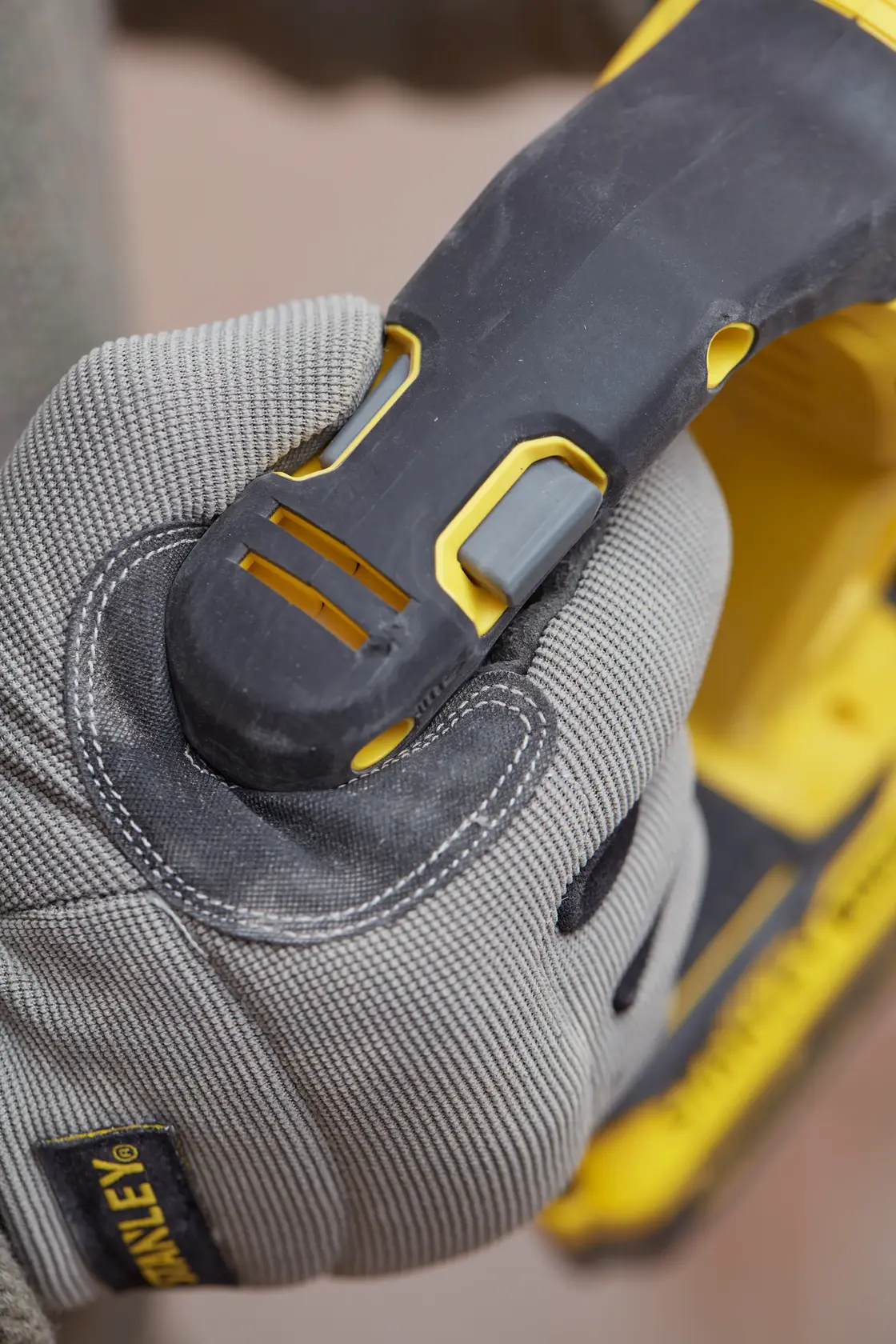 Stanley SBH900M2K-B3 agarre de herramienta eléctrica en primer plano, guante gris sujetando mango negro y amarillo.