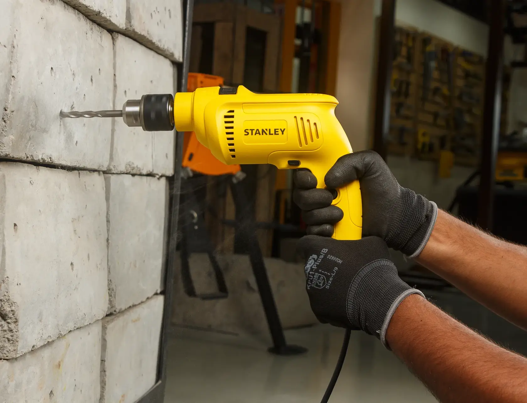 STANLEY SDH600KP taladro amarillo con cable usado en pared de concreto, primer plano en taller.