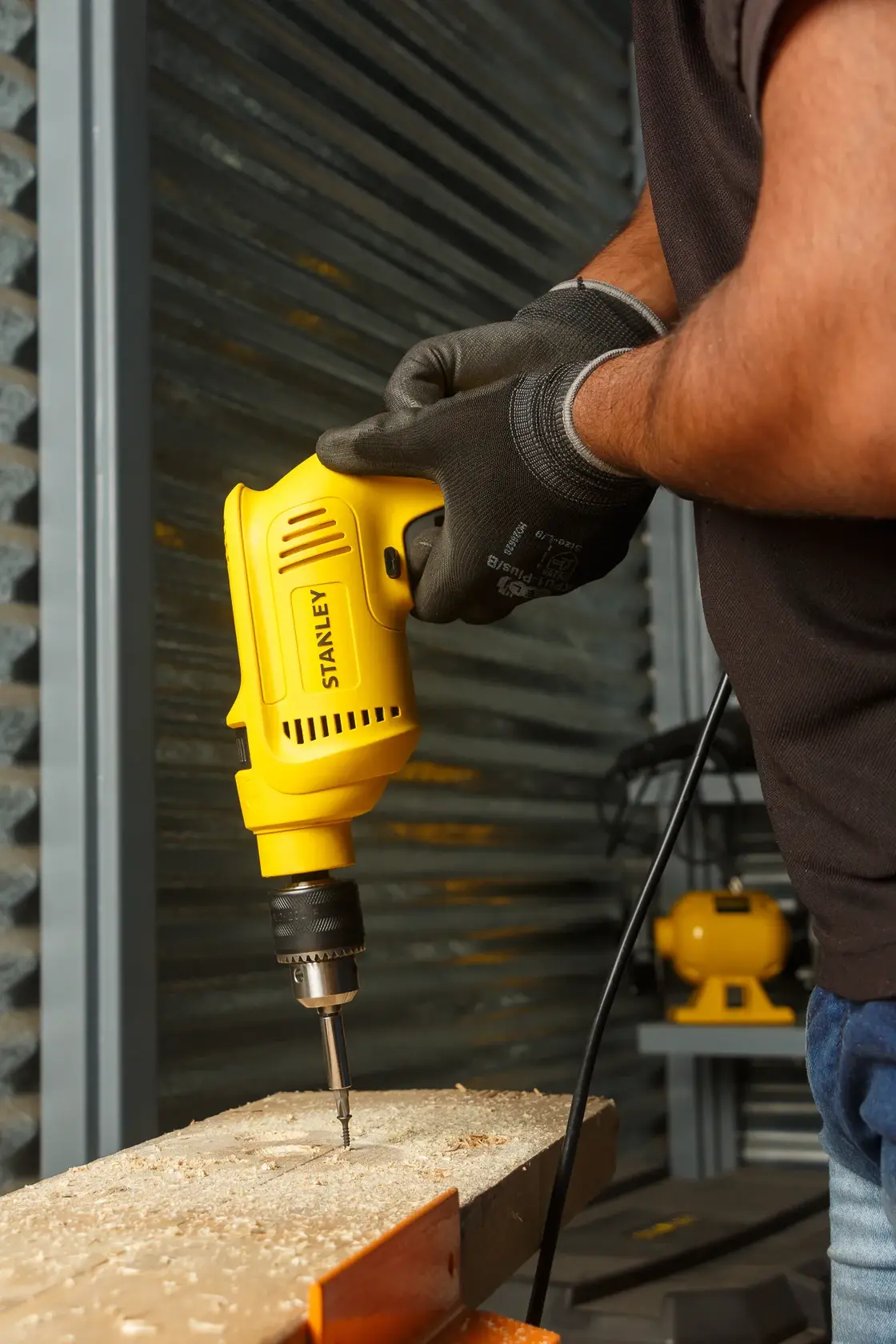 Stanley SDH600KP taladro amarillo con cable en uso, perforando una tabla de madera en taller, vista cercana.