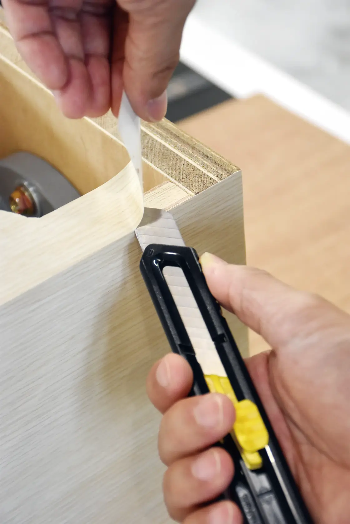 Cuchillo de uso STANLEY STHT10323-840 cortando cinta en madera, ángulo en primer plano.