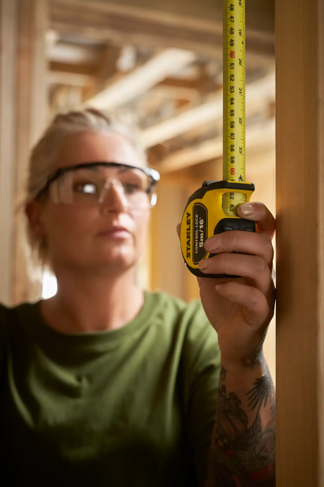 Fotografía de una persona usando un flexómetro STANLEY STHT37246-0 en un marco de madera, mostrando la medición en una obra.