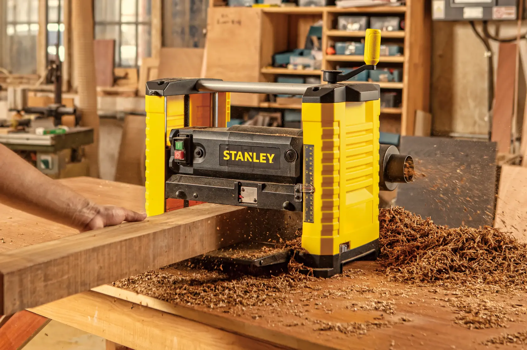 Cepillo STANLEY STP18-B2 en uso, amarillo y negro, virutas de madera en banco de trabajo en taller.